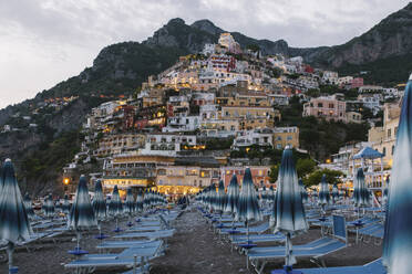 Italien, Kampanien, Positano, Leere Liegestühle am Strand der Amalfiküste in der Abenddämmerung - MMPF01066