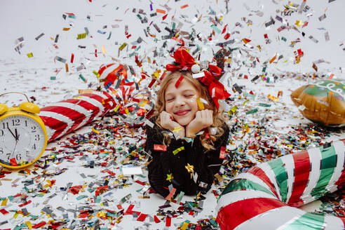 Lächelndes Mädchen in der Nähe von Weihnachtsschmuck auf dem Boden liegend - MDOF01742