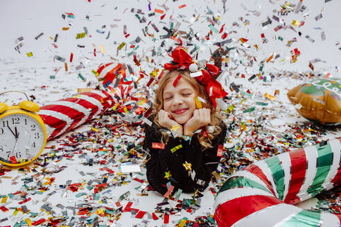 Smiling girl lying near Christmas decoration on floor - MDOF01742