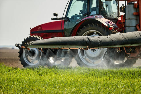 Serbien, Provinz Vojvodina, Traktor sprüht Herbizid in einem Weizenfeld im Frühling - NOF00810