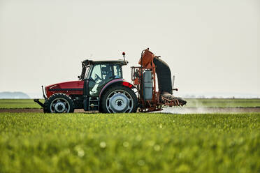 Serbien, Provinz Vojvodina, Traktor sprüht Herbizid in ein großes grünes Weizenfeld - NOF00814