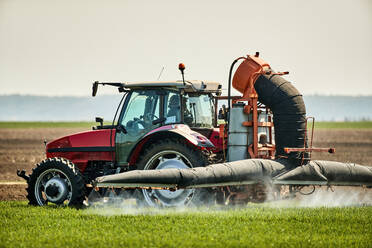 Serbien, Provinz Vojvodina, Traktor sprüht Herbizid in einem Weizenfeld im Frühling - NOF00815