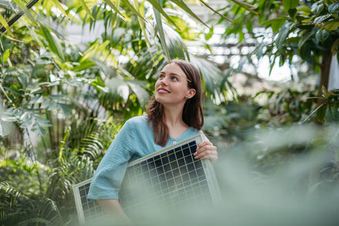 Junge Frau im botanischen Garten mit einer Photovoltaikanlage. - HPIF31900