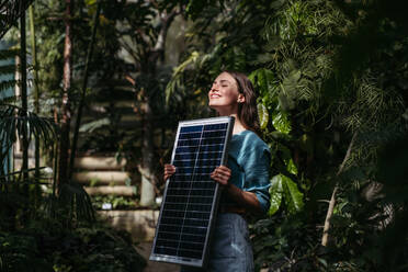 Young woman in botanical garden with a photovoltaics panel. - HPIF31910