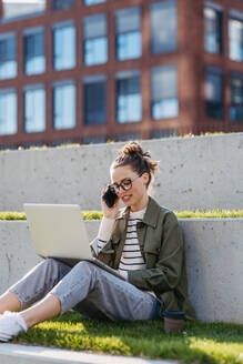 Young woman sitting in city park and working on a laptop. - HPIF31978