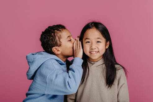 Portrait of little boy whispering something to girl standing next to him. - HPIF32005