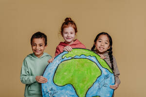 Portrait of three children with model of Earth, studio shoot. Concept of diversity in a friendship. - HPIF32033