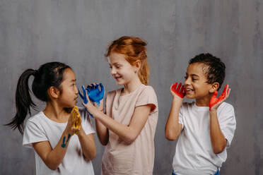 Portrait of happy kids with painted hands, studio shoot. - HPIF32048