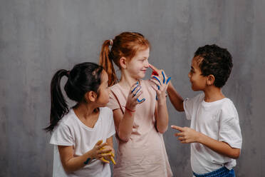 Portrait of happy kids with finger colours and painted t-shirts. - HPIF32049