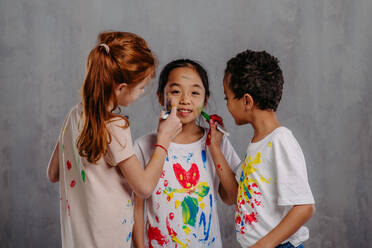 Portrait of happy kids with finger colours and painted t-shirts. - HPIF32058