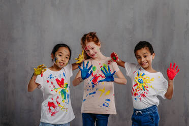 Portrait of happy kids with finger colours and painted t-shirts. - HPIF32059