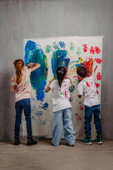 Rückansicht von glücklichen Kindern mit Fingerfarben und bemalten T-Shirts. - HPIF32060
