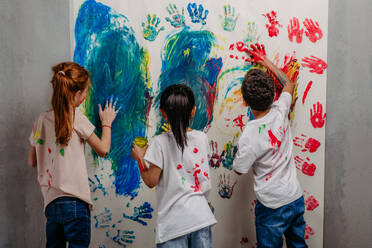 Rear view of happy kids with finger colours and painted t-shirts. - HPIF32061