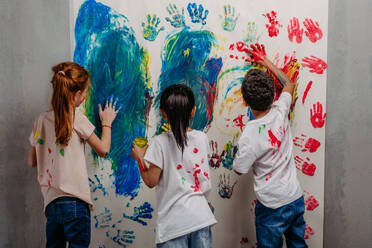 Rückansicht von glücklichen Kindern mit Fingerfarben und bemalten T-Shirts. - HPIF32061