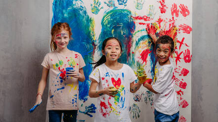 Portrait of happy kids with finger colours and painted t-shirts. - HPIF32062