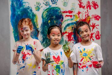 Portrait of happy kids with finger colours and painted t-shirts. - HPIF32063