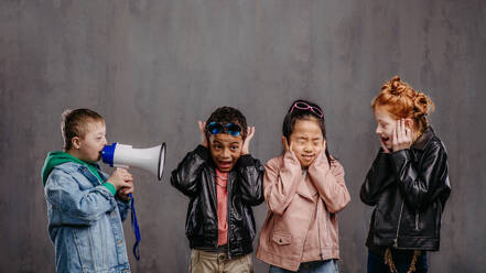 Studio shoot of a child with megaphone shouting at other children. - HPIF32067