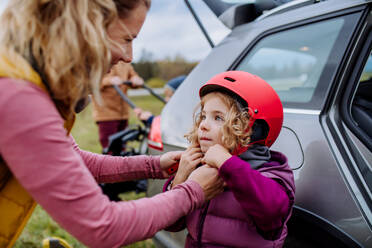 Junge Familie mit kleinen Kindern, die sich auf eine Fahrradtour in der Natur vorbereitet, indem sie die Fahrräder von den Autoträgern abstellt. Konzept der gesunden Lebensweise und der Bewegung. - HPIF32089