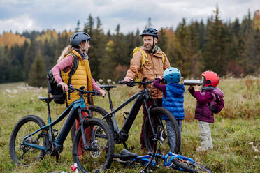 Junge Familie mit kleinen Kindern, die sich auf eine Fahrradtour in der Natur vorbereitet, indem sie die Fahrräder von den Autoträgern abstellt. Konzept der gesunden Lebensweise und der Bewegung. - HPIF32091