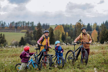 Junge Familie mit kleinen Kindern auf Fahrrädern, inmitten der herbstlichen Natur, Konzept der gesunden Lebensweise. - HPIF32092