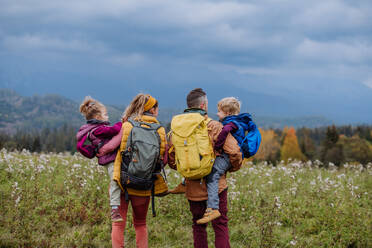 Glückliche Eltern mit ihren kleinen Kindern auf dem Arm bei einem Herbstspaziergang inmitten der farbenfrohen Natur - ein Konzept für einen gesunden Lebensstil. - HPIF32098