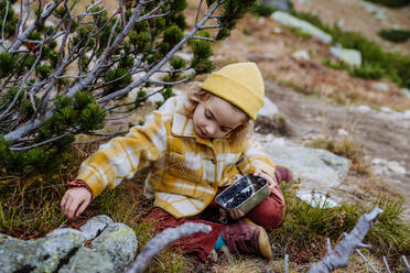 Little girl sitting and harvesting blueberries during autumn hike in the mountains. - HPIF32110