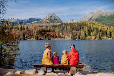 Rear view of young family with little children, resting and enjoying view at a lake in mountains. - HPIF32112