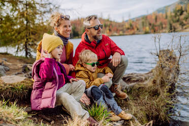 Glückliche junge Familie mit kleinen Kindern, die sich an einem See in den Bergen ausruhen. - HPIF32113