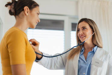 Ein Arzt hört mit einem Stethoskop die Atmung und den Herzschlag eines Mädchens ab. Ein Mädchen im Teenageralter besucht einen Kinderarzt zur jährlichen Vorsorgeuntersuchung. Konzept der Gesundheitsvorsorge für Heranwachsende. - HPIF32118