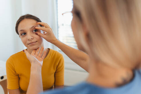 A pediatrician examining eyes of a teenage patient. Ophthalmologist treating an eye infection, allergy, or inflammation in ophthalmic clinic - HPIF32127
