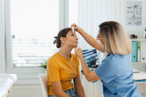 Ein Kinderarzt gibt Augentropfen in die Augen eines Mädchens. Ein Augenarzt behandelt eine Augeninfektion, Allergie oder Entzündung mit verschriebenen Augentropfen. - HPIF32129