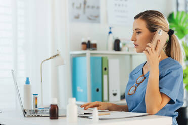 Female doctor making call during phone consultations in doctor's office. Telemedicine and telephone doctor conultations as importatn part of healthcare. - HPIF32131