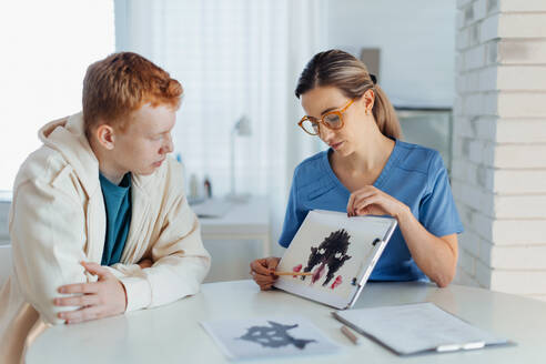 Teenager taking Rorschach test during psychological therapy with adolescent psychologist. Psychological session for teenage boy. Concept of teen mental health and unique adolescent problems. - HPIF32151