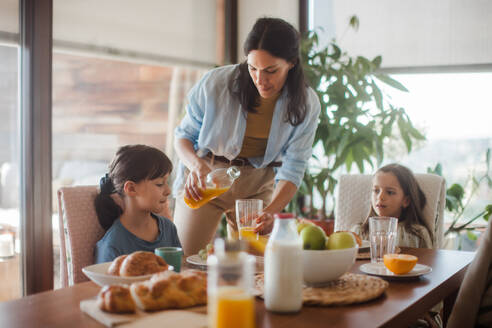 Mutter bereitet morgens das Frühstück für die Kinder vor. Mütterliche Liebe und Fürsorge für den Haushalt und die Familie. - HPIF32173