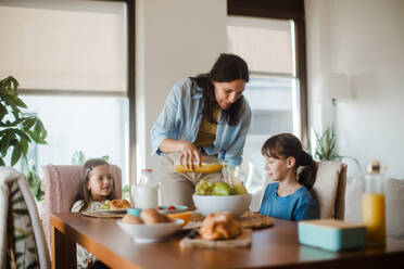 Mutter bereitet morgens das Frühstück für die Kinder vor. Mütterliche Liebe und Fürsorge für den Haushalt und die Familie. - HPIF32176