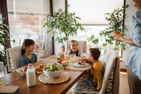 Mutter bereitet morgens das Frühstück für die Kinder vor. Mütterliche Liebe und Fürsorge für den Haushalt und die Familie. - HPIF32178