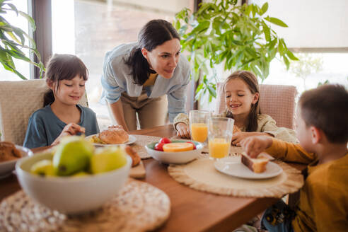 Mutter bereitet morgens das Frühstück für die Kinder vor. Mütterliche Liebe und Fürsorge für den Haushalt und die Familie. - HPIF32179