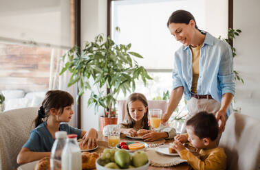 Mutter bereitet morgens das Frühstück für die Kinder vor. Mütterliche Liebe und Fürsorge für den Haushalt und die Familie. - HPIF32180