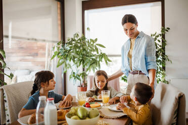 Mutter bereitet morgens das Frühstück für die Kinder vor. Mütterliche Liebe und Fürsorge für den Haushalt und die Familie. - HPIF32181