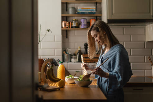 Young woman preparing salad in the kitchen. - HPIF32251