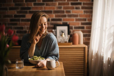 Young woman eating salad in the kitchen, concept of healthy eating. - HPIF32252