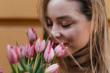 Young woman calling in a city with bouquet of tulips. - HPIF32265