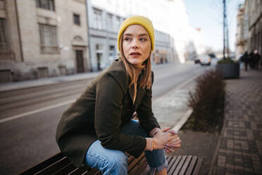 Young fashionable woman sitting on bench in a city. - HPIF32270