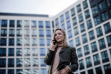 Portrait of young fashionable woman in city calling. - HPIF32276