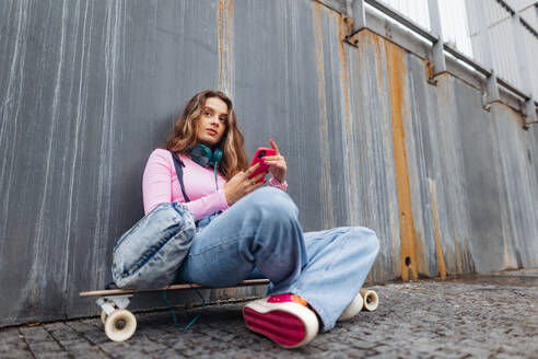 Portrait of generation z girl student sitting outdoors in the city. Student spending free time online and alone. Concept of gen Z as loneliest generation. - HPIF32282