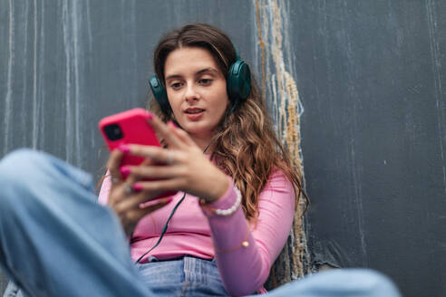 Portrait of generation z girl student sitting outdoors in the city. Student spending free time online and alone. Concept of gen Z as loneliest generation. - HPIF32283