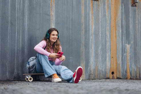 Portrait of generation z girl student sitting outdoors in the city. Student spending free time online and alone. Concept of gen Z as loneliest generation. - HPIF32284