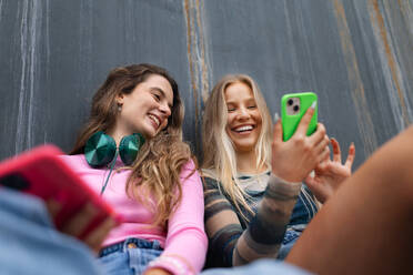 Young stylish generation Z girls spending time outdoors after school. Zoomer students talking and gossiping during lunch break in the school. Concept of power of friendship and importance of education for gen Z. - HPIF32285