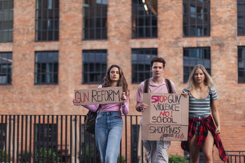 Aktivisten der Generation Z protestieren mit Transparenten auf der Straße. Junge Studenten marschieren durch die Stadt und demonstrieren gegen den Klimawandel. Demonstranten fordern Waffenkontrolle, Rassen- und Geschlechtergleichheit. Konzept der sozialen Stärke der Generation Z. - HPIF32289