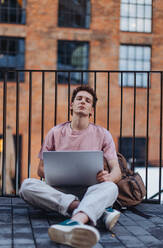 Gen Z student working on laptop after lecture on campus. Young stylish zoomer studiing outdoors. Concept of importance of education of gen Z. - HPIF32293